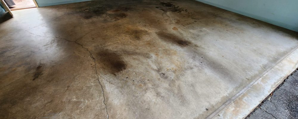 Before image of garage concrete floor with oil stains and lots of cracks.