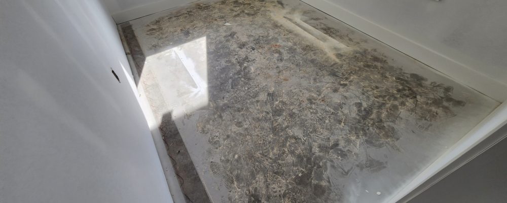 Unfinished, rough and splotchy concrete on an interior floor.