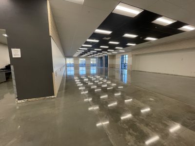 view of large commercial space and highly polished concrete floor reflecting the lights